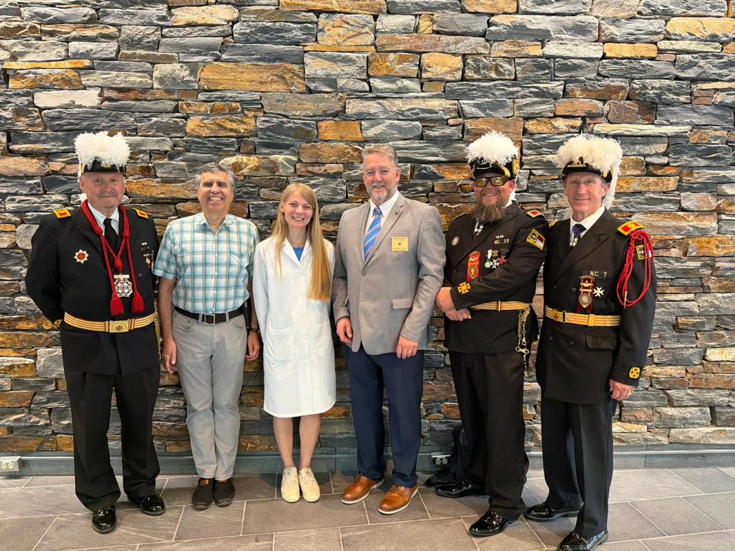 Lab members posing with knights in front of stone wall