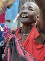 Woman smiling and holding hand in the air happy after cataract surgery because she can see again.